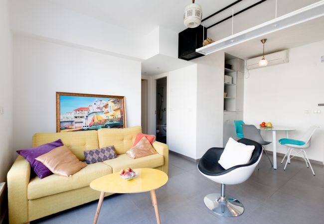 Яркая гостиная с удобным, желтым диваном в квартире на ул. Бен Иегуда